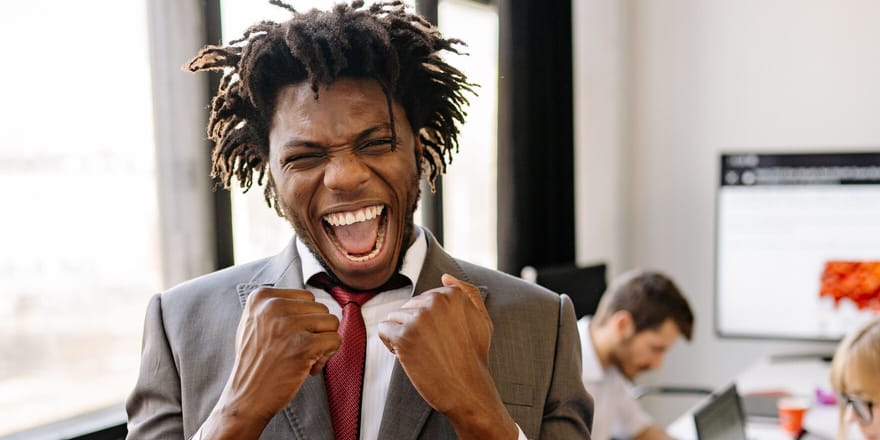 An analyst celebrating at his desk